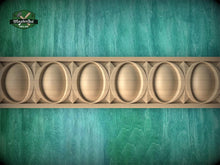Load image into Gallery viewer, a close-up view of a wooden carving with a repeating pattern of oval shapes, set against a green textured background.
