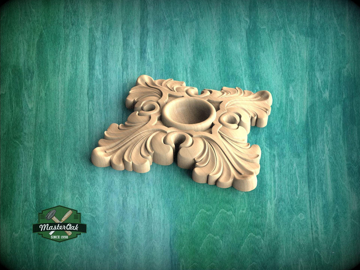 A decorative wooden piece with an ornate, floral design sits on a green wooden surface.