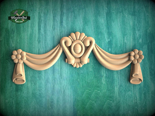 A decorative wooden panel with a floral motif and scrollwork, mounted on a green textured wall.