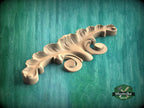 A wooden carving of a leaf-like design rests on a green textured background.