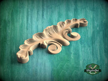 Load image into Gallery viewer, A wooden carving of a leaf-like design rests on a green textured background.
