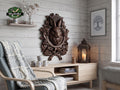 May include: A detailed, dark brown wooden wall carving of a rabbit's head, surrounded by leaves and crossed axes. The carving is mounted on a light wood-paneled wall. A framed tree art print and a lit candle lantern are also visible.