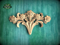 A decorative wooden carving of a flower on a green background.