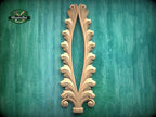 a decorative wooden leaf-like design with a vertical, symmetrical shape, mounted on a green textured background.