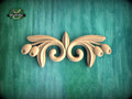 A decorative wooden carving in the shape of a stylized flower or leaf design is displayed against a green textured background.