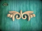 A decorative wooden carving in the shape of a stylized flower or leaf design is displayed against a green textured background.