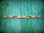 A decorative wooden carving or panel with an intricate floral design is displayed against a textured green background.