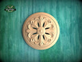 A wooden ornamental piece with a floral design is displayed against a green textured background.