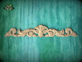 a decorative wooden carving on a green textured background.