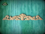 a decorative wooden carving on a green textured background.