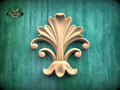 a decorative wooden leaf-like design on a green background.