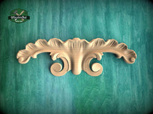 Load image into Gallery viewer, A wooden decorative finial or scroll is displayed against a green textured background.
