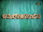 A decorative wooden carving with intricate scrollwork is displayed against a green textured background.