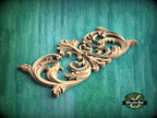 A decorative wooden carving with intricate scrollwork is displayed against a green background.