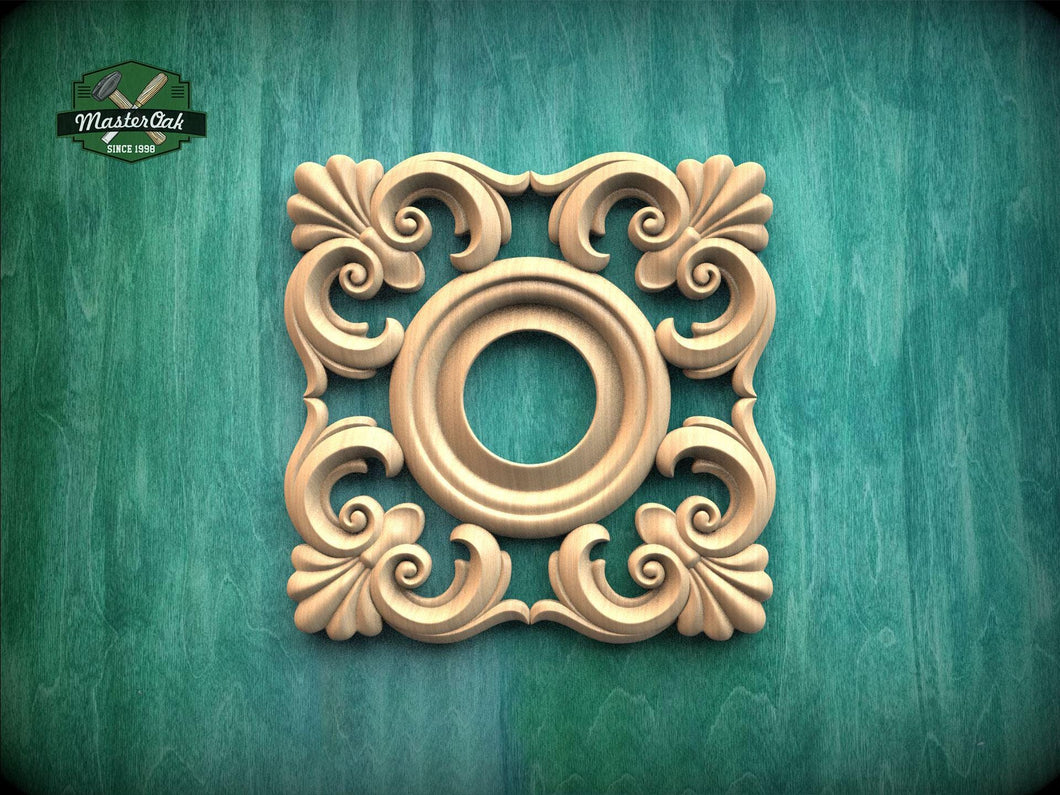a square, ornate wooden carving with a central circular opening, set against a green wooden background.