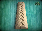A wooden carving of a braided pattern is displayed against a green background.