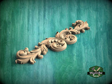 Load image into Gallery viewer, A decorative wooden carving with intricate scrollwork is displayed against a green textured background.
