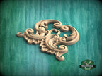 A decorative wooden carving with intricate scrollwork is displayed against a green background.