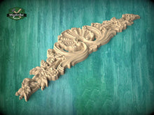 Load image into Gallery viewer, A decorative wooden carving with intricate floral and leaf designs is displayed against a teal background.
