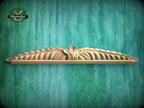 A decorative wooden carving or molding is displayed against a textured green background.