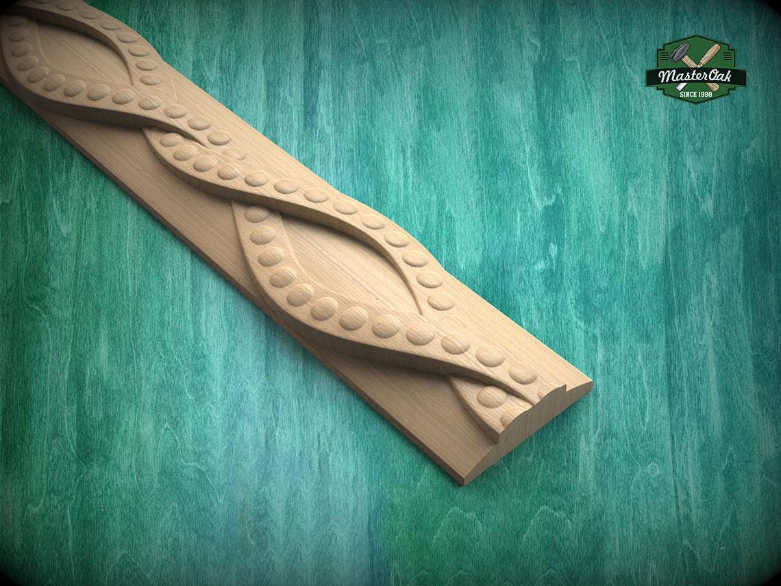 A wooden carving with a curved, organic design sits on a green wooden surface.