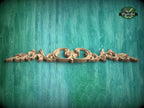 A decorative wooden carving with intricate floral patterns is displayed against a textured green background.