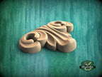 A wooden carving of a stylized flower or floral design is displayed against a green background.