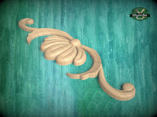 Load image into Gallery viewer, A wooden carving of a flower-like design is displayed against a green background.

