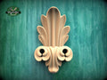 a decorative wooden sculpture with an intricate, ornate design on a green textured background.