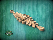 Load image into Gallery viewer, A wooden carving of a leaf-like design is displayed against a green background.
