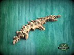 A decorative wooden carving with intricate leaf and flower designs is displayed against a green background.