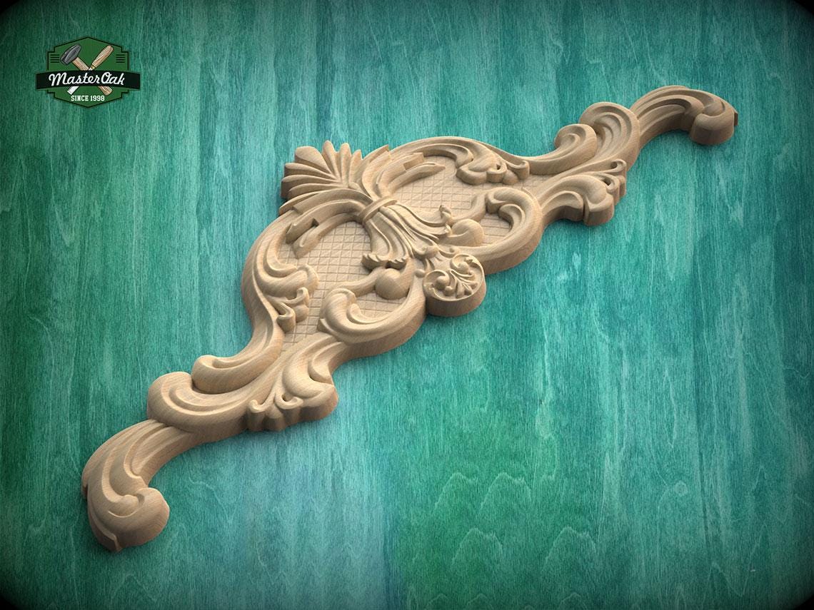 A decorative wooden carving with intricate floral and scrollwork designs is displayed against a green wooden background.