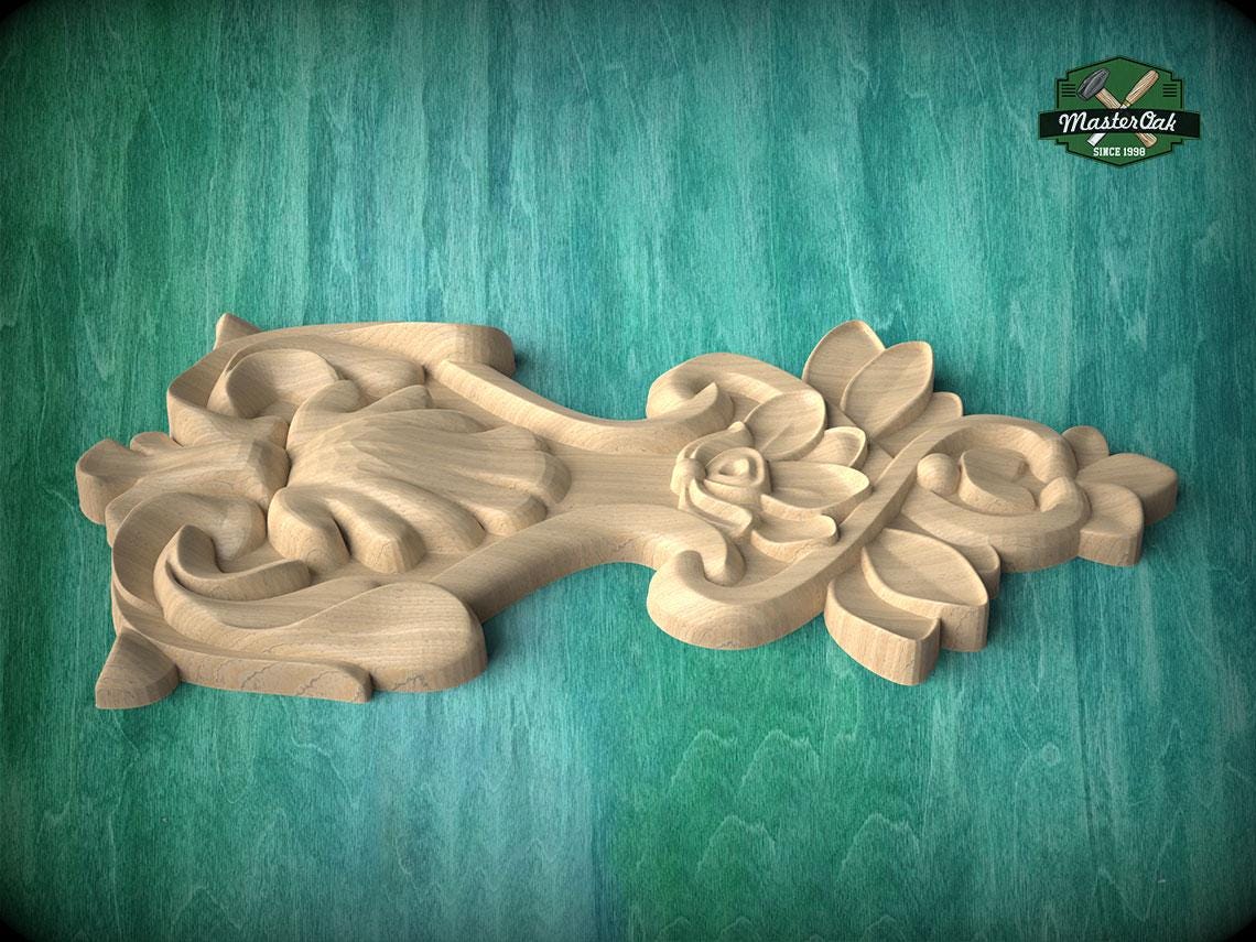 A carved wooden piece with intricate floral and leaf designs, displayed on a green wooden surface.