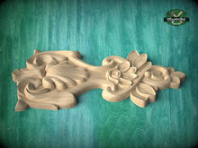 Load image into Gallery viewer, A carved wooden piece with intricate floral and leaf designs, displayed on a green wooden surface.
