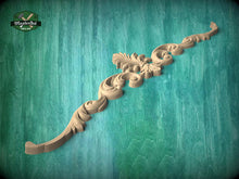 Load image into Gallery viewer, A decorative wooden carving with intricate scrollwork is displayed against a teal-colored background.
