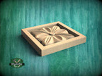 A wooden box with a carved flower-like design on its side, set against a green textured background.