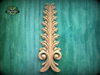 a decorative wooden leaf-like object with a vertical, ornate design on a green background.