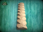 A wooden sculpture with a unique, intricate design is displayed against a green background.
