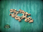 A decorative wooden carving with intricate scrollwork and floral elements is displayed against a green wooden background.