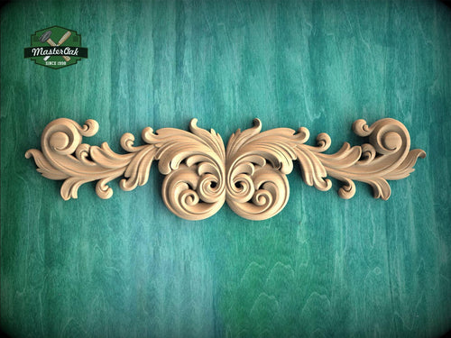 a decorative wooden carving with intricate scrollwork and floral elements, set against a textured green background.