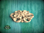 A wooden flower-like design is centered against a green background.