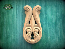 Load image into Gallery viewer, a wooden carving of a stylized flower or leaf design on a green background.
