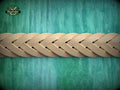 A close-up view of a braided wooden object, possibly a piece of furniture or a decorative item, set against a green and blue textured background.