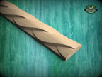 A wooden carving with a curved, braided design is displayed against a green background.