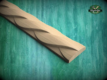 Load image into Gallery viewer, A wooden carving with a curved, braided design is displayed against a green background.
