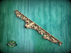 A decorative wooden molding with an intricate floral design is displayed against a green textured background.