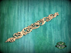 A decorative wooden carving with intricate scrollwork is displayed against a green textured background.