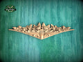 A decorative wooden carving with floral and leaf-like designs is displayed against a green textured background.