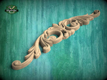 Load image into Gallery viewer, A decorative wooden carving with intricate floral and scrollwork designs is displayed against a teal-colored background.
