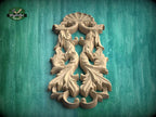 a carved wooden design with intricate leaf-like patterns, set against a green background.